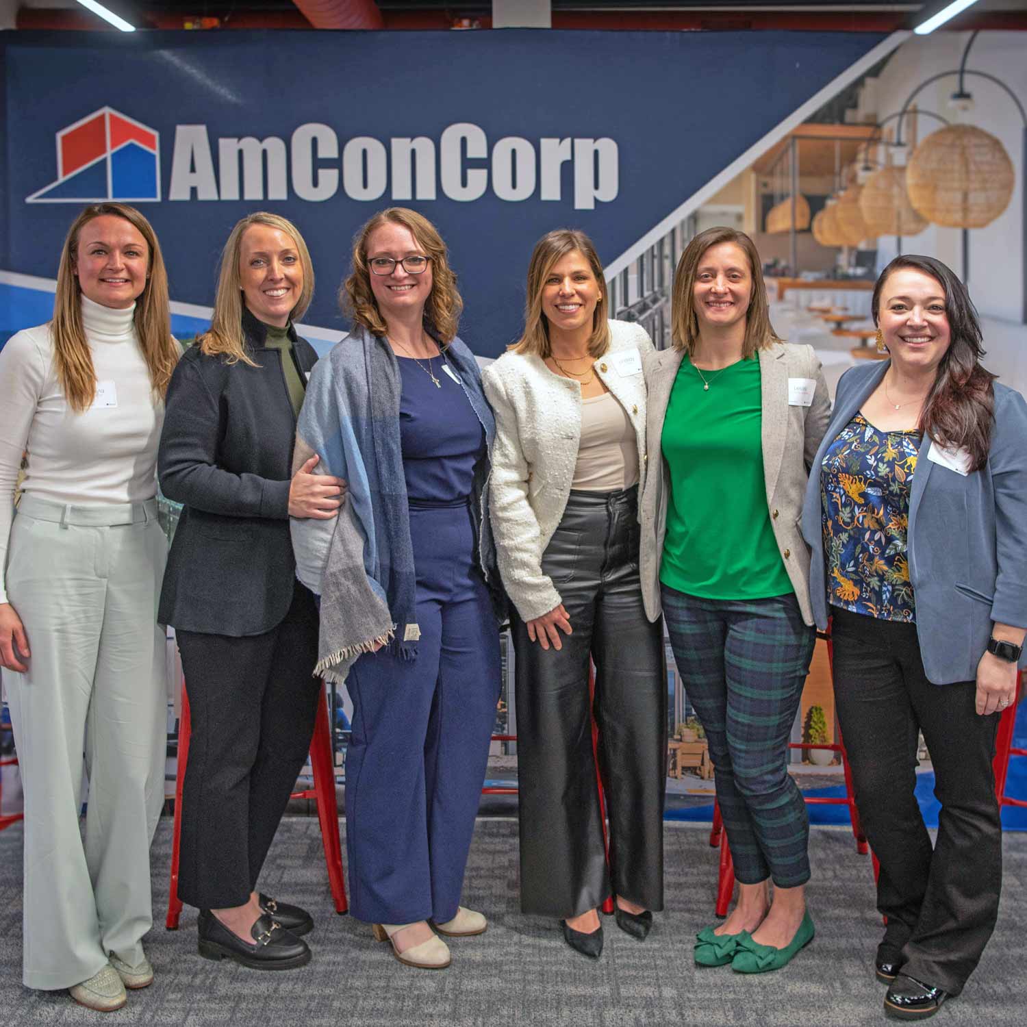 Amcon team photo in front of a banner with company branding.